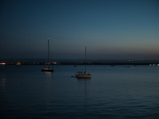 View of sailboats anchored at night near Ortigia island, Siracusa © Daniel Garcia De Marina Bravo/Wirestock