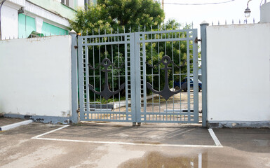 The old forged metal double gates with anchors for cars to enter the yard are closed