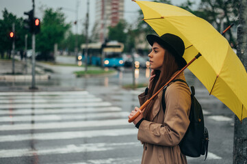 Woman holding yellow umbrella while in the city while it rains