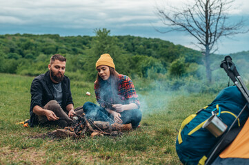 Couple of campers eating marshmallows while camping in the nature