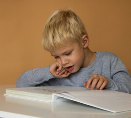little hearing impaired boy with hearing aids studying and reading a book