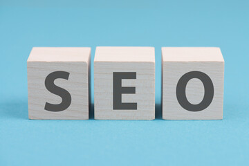 The word SEO is standing on wooden cubes, blue background