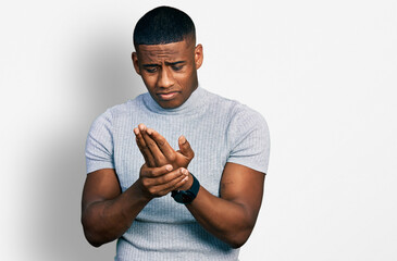 Young black man wearing casual t shirt suffering pain on hands and fingers, arthritis inflammation