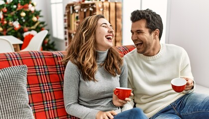 Young hispanic couple smiling happy drinking coffee sitting on the sofa at home.