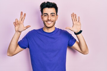 Fototapeta premium Young hispanic man wearing casual t shirt showing and pointing up with fingers number eight while smiling confident and happy.