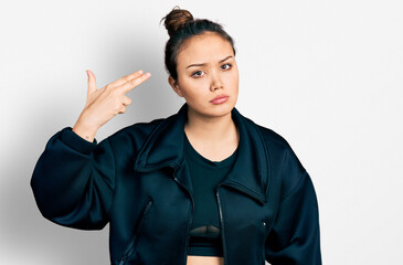Young hispanic girl wearing sportswear shooting and killing oneself pointing hand and fingers to...