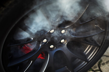 Close-up of a race car wheel with smoke coming out of it after heavy braking.