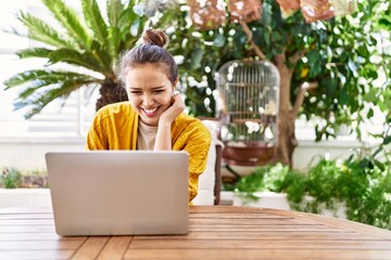 Young hispanic girl using laptop sitting on the table at terrace.
