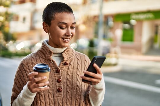 Young hispanic woman with short hair smiling happy drinking a cup of coffee and  using smartphone