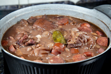 Traditional Brazilian feijoada in a rustic pan with details on the ingredients