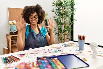 Beautiful african american woman with afro hair painting at art studio showing and pointing up with fingers number ten while smiling confident and happy.