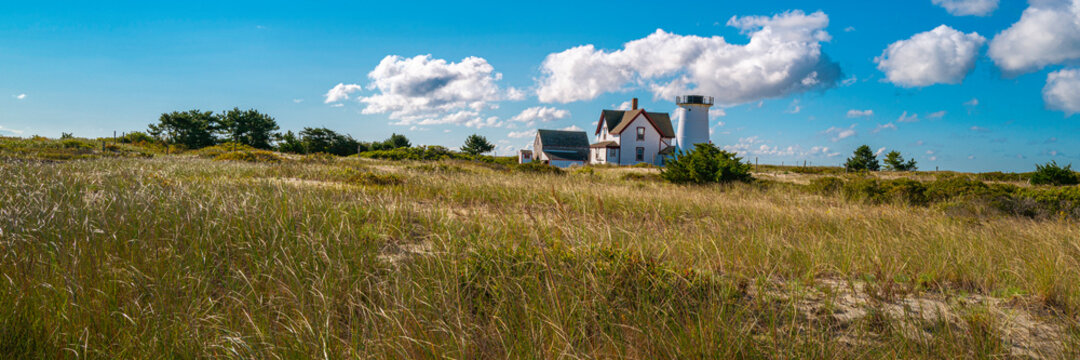 Panoramic autumn meadow landscape with the view of Stage Harbor Lighthouse under the white clouds floating in the blue sky