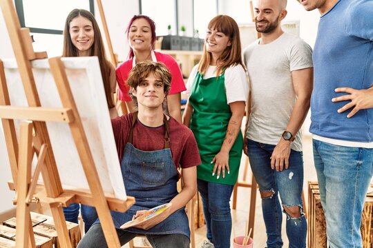 Group of young paint students smiling happy and looking draw of partner at art studio.