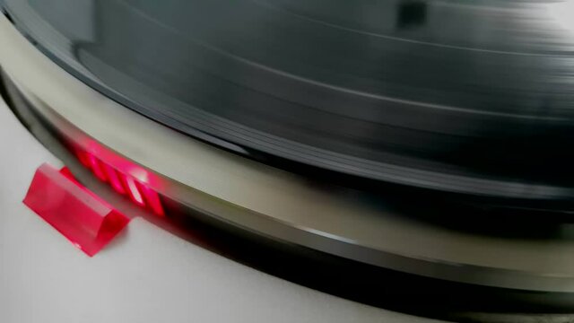 Close up of turning vinyl record with red light of stroboscope for a retro music feeling, selective focus