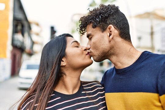 Young latin couple kissing and hugging at the city.
