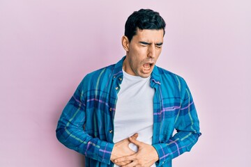 Handsome hispanic man wearing casual clothes with hand on stomach because nausea, painful disease...