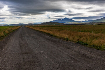 summer road trip on an open high way in Route 1 in Iceland with dramatic mountain landscape on the background.