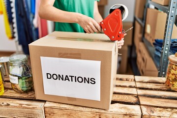 Young caucasian woman packing donations box at charity center