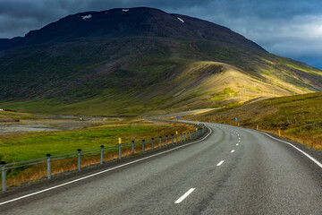summer road trip on an open high way in Route 1 in Iceland with dramatic mountain landscape on the background.