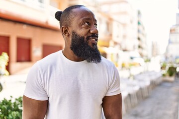 Handsome african american man with beard wearing casual white t shirt outdoors on a sunny day