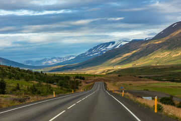 summer road trip on an open high way in Route 1 in Iceland with dramatic mountain landscape on the background.