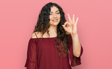 Young hispanic girl wearing casual clothes smiling positive doing ok sign with hand and fingers. successful expression.