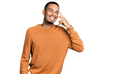 Young african american man wearing casual clothes doing peace symbol with fingers over face,...