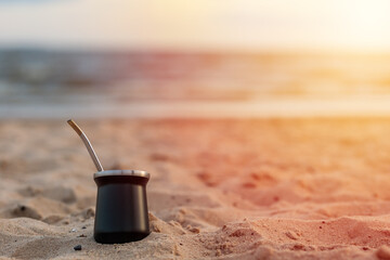 mate resting on the sand of the beach. Reflection of the sun. Sunset. In the background you can see the river and the sky. Copy space for text.