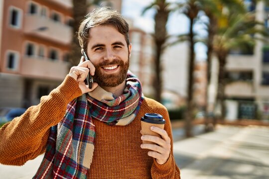 Caucasian man with beard having a conversation speaking on the phone outdoors on a sunny day