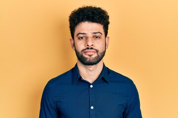Fototapeta premium Young arab man with beard wearing casual shirt relaxed with serious expression on face. simple and natural looking at the camera.