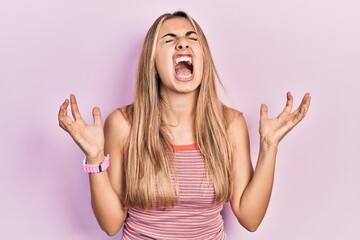 Beautiful hispanic woman wearing casual summer t shirt crazy and mad shouting and yelling with...