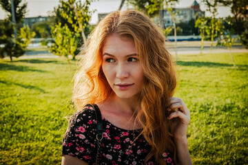 young redhead woman sitting on bench in park looking away the camera in calm state of mind