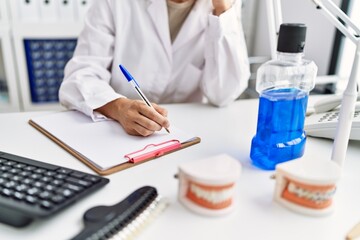 Young blonde woman wearing dentist uniform speaking on the phone at dental clinic
