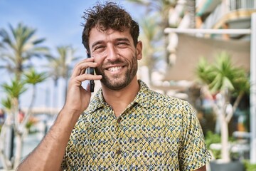 Young hispanic man smiling confident talking on the smartphone at street