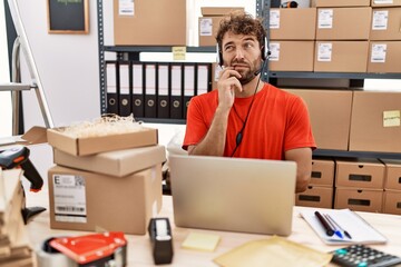 Young hispanic call center agent man working at warehouse thinking worried about a question, concerned and nervous with hand on chin