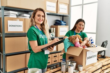 Two young volunteers woman smiling happy working at charity center.