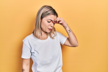 Beautiful caucasian woman wearing casual white t shirt tired rubbing nose and eyes feeling fatigue and headache. stress and frustration concept.