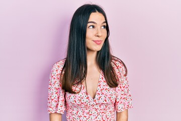 Obraz premium Young brunette woman wearing summer dress smiling looking to the side and staring away thinking.