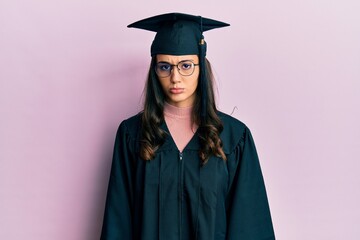 Young hispanic woman wearing graduation cap and ceremony robe skeptic and nervous, frowning upset because of problem. negative person.