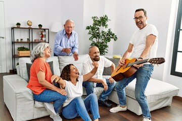 Group of middle age friends having party playing classical guitar sitting on the sofa at home.