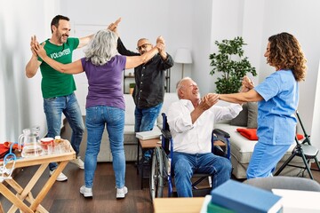 Group of retired people having party dancing with doctor and volunteer at nurse home.