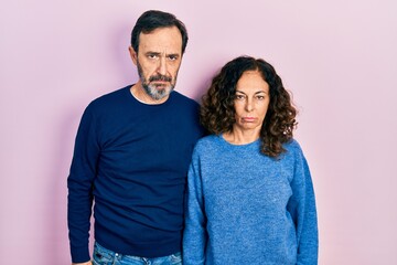 Middle age couple of hispanic woman and man hugging and standing together depressed and worry for distress, crying angry and afraid. sad expression.