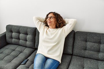 Middle age hispanic woman smiling confident wearing glasses at home