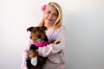 woman smiling looking forward holding a dog wearing pink outfit, dog in pink outfit, pink october