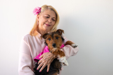 woman smiling looking forward holding a dog wearing pink outfit, dog in pink outfit, pink october - obrazy, fototapety, plakaty