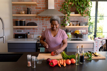 Happy african american senior woman cooking in kitchen