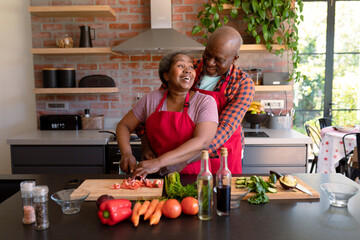 Happy african american senior couple cooking together in kitchen