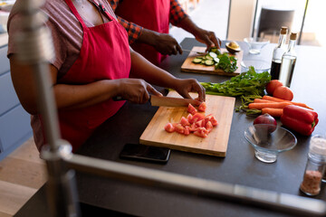 Midsection of african american senior couple cooking together in kitchen
