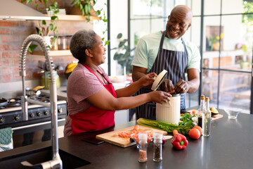 Happy african american senior couple cooking together in kitchen