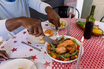 Hands of african american senior man eating christms meal at home